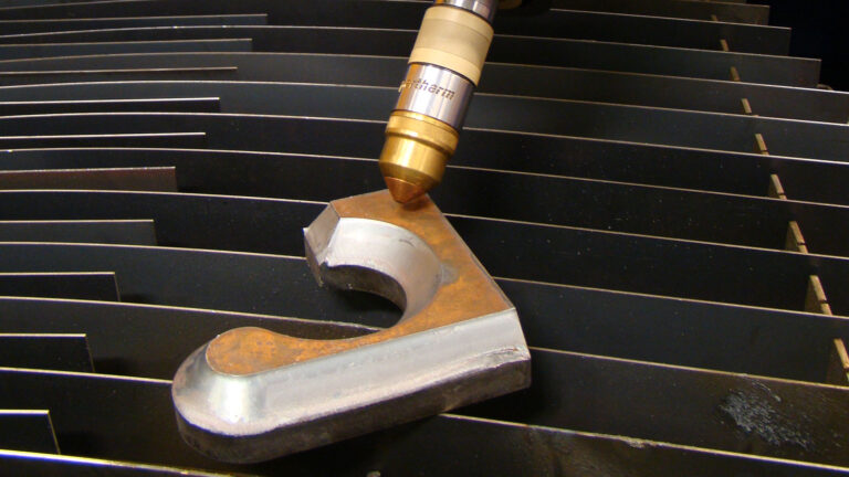 Part processed by Additional Beveling Process on a cutting table with a plasma torch above it